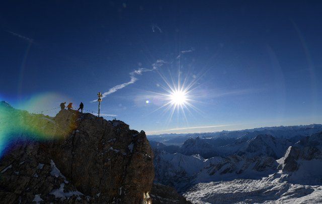 07 November 2021, Bavaria, Grainau: Three visitors climb the last meters to the summit on the Zugspitze. Photo: Angelika Warmuth\/dpa