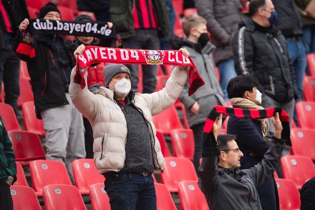 22 January 2022, North Rhine-Westphalia, Leverkusen: Soccer: Bundesliga, Bayer Leverkusen - FC Augsburg, Matchday 20, BayArena. Leverkusen supporters hold up their fan scarves before the match. Photo: Marius Becker\/dpa - IMPORTANT NOTE: In accordance with the requirements of the DFL Deutsche Fußball Liga and the DFB Deutscher Fußball-Bund, it is prohibited to use or have used photographs taken in the stadium and\/or of the match in the form of sequence pictures and\/or video-like photo series