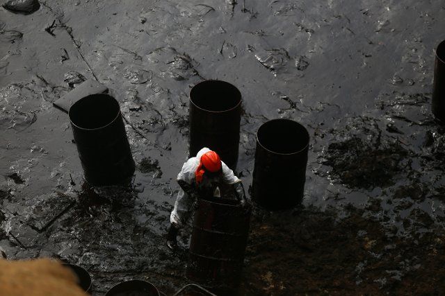 FILED - 21 January 2022, Peru, Ventanilla: A man in a white suit works to clean up the oil spill on Cavero beach after about 6,000 barrels (159 liters each) of oil spilled during the unloading of a tanker at the La Pampilla refinery owned by Spanish energy company Repsol. Photo: Gian Masko\/dpa