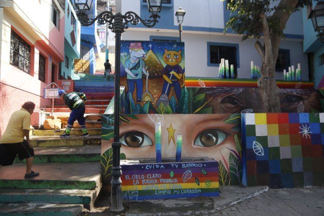 FILED - 08 February 2022, Peru, Lima: A street sweeper works in the "Leticia" settlement on the slopes of Cerro San Cristobal, where house facades have been colorfully painted by artists and volunteers. Photo: Gian Masko\/dpa