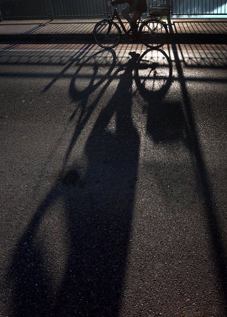 19 December 2021, Bavaria, Landsberg am Lech: A cyclist on the Lech bridge casts a long shadow in the sunshine. Photo: Karl-Josef Hildenbrand\/dpa
