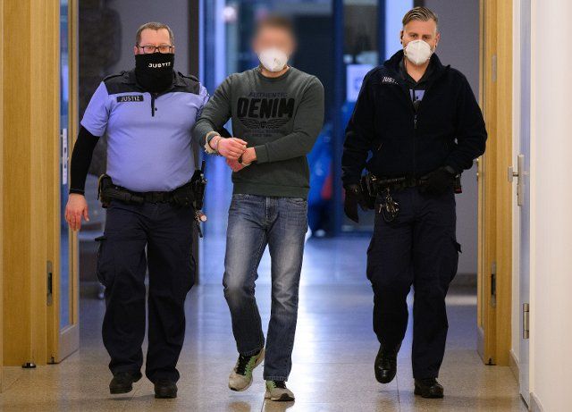 10 January 2022, Saxony, Dresden: A defendant (M) is led into the courtroom at the district court before the start of the trial following the riots on May 16, 2021. The last home game of the then third-division club SG Dynamo Dresden against Türkgücü Munich took place on May 16, 2021, without fans because of the Corona pandemic. However, thousands of people had gathered in the nearby Großer Garten to celebrate Dresden\