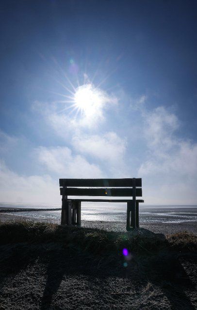 04 March 2022, Schleswig-Holstein, Wyk: A bench stands on the small dike on the mudflats at Greveling Strand between Nieblum and Wyk on the North Sea island of Föhr. Photo: Christian Charisius\/dpa