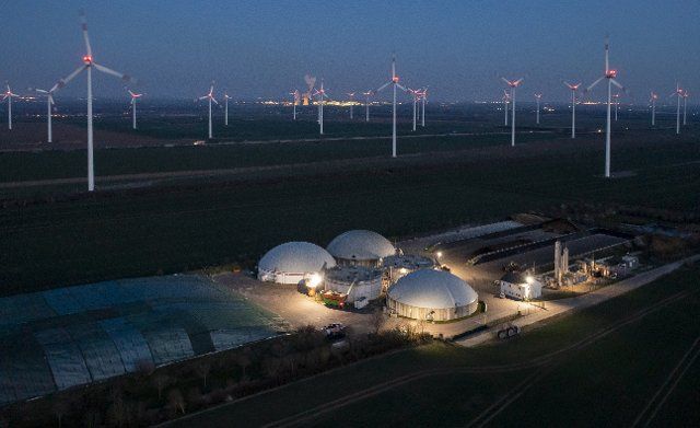 21 March 2022, Saxony-Anhalt, Bad Lauchstädt: Wind turbines turn behind a biogas plant. The warlike clashes are reviving the discussion in Germany about phasing out lignite and expanding renewable energies. (Aerial view with drone) Photo: Jan Woitas\/dpa-Zentralbild\/dpa