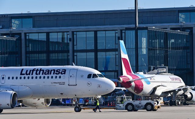 28 March 2022, Brandenburg, Schönefeld: A passenger aircraft of the airline Lufthansa and Eurowings stand in front of the terminal of the capital city airport Berlin-Brandenburg (BER). Eurowings GmbH is a German low-cost airline based in Düsseldorf. It is a subsidiary of Lufthansa. Photo: Patrick Pleul\/dpa-Zentralbild\/ZB