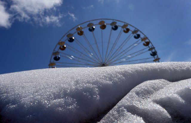 03 April 2022, Bavaria, WÃ¼rzburg: The Ferris wheel of the Spring Folk Festival spins behind accumulated snow. Photo: Karl-Josef Hildenbrand\/dpa