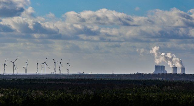 23 February 2022, Brandenburg, Bohsdorf: Steam rises from the cooling towers of the Schwarze Pumpe lignite-fired power plant. A few kilometers away, several wind turbines are turning. Photo: Patrick Pleul\/dpa-Zentralbild\/ZB