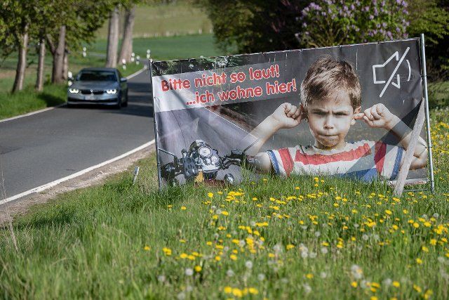 03 May 2022, Lower Saxony, Golmbach: A poster with the inscription "Please not so loud! ... hier wohne ich" can be seen at the end of the village, while a car drives past it. (to dpa "District of Holzminden sets up "noise displays" because of motorcycle noise") Photo: Swen Pförtner\/dpa