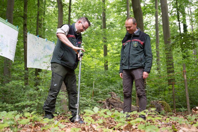 25 May 2022, Saxony, Dresden: Jacob Frank (l), state inventory manager of Saxony Forest, takes a soil sample next to Wolfram Günther (Bündnis90\/Die Grünen), Saxony\