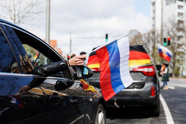 10 April 2022, Lower Saxony, Hanover: A woman holds a Russian flag out of the passenger window of a car that is part of a pro-Russian motorcade. A private person has reported a gathering under the slogan: "Against sedition, bullying and discrimination against the Russian population". There was also a call for a counter-demonstration. Photo: Michael Matthey\/dpa