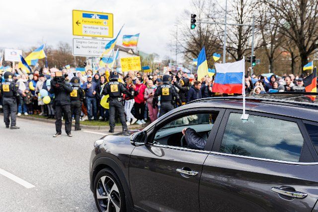 10 April 2022, Lower Saxony, Hanover: Counter-demonstrators face a car of the pro-Russian motorcade on Friedrichswall. A private person has reported a meeting under the motto: "Against incitement of the people, bullying and discrimination of the Russian population". A counter-demonstration had also been called for Photo: Michael Matthey\/dpa