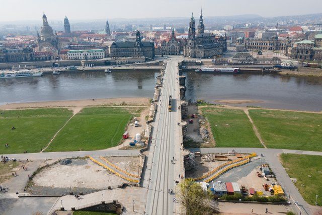 14 April 2022, Saxony, Dresden: Passers-by walk across the Augustus Bridge against the backdrop of the Old Town. (Aerial view with a drone) Photo: Sebastian Kahnert\/dpa