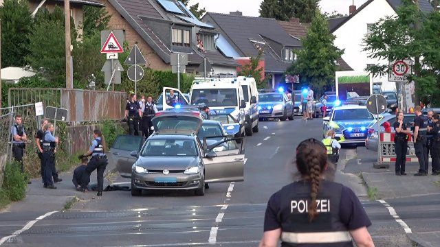 17 June 2022, North Rhine-Westphalia, Bonn: A suspect sits next to a car in Bonn and is guarded by police officers. The man was arrested after blowing up an ATM in Kroppach in the Westerwald region of Rhineland-Palatinate. (Best possible quality) Photo: .\/Steil-TV\/dpa - ATTENTION: License plate(s) pixelated for legal reasons