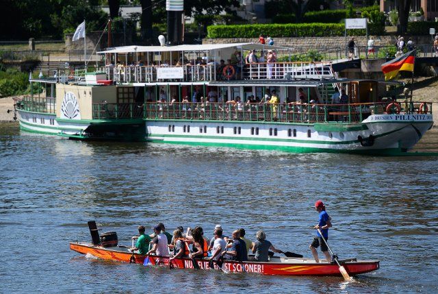 18 June 2022, Saxony, Dresden: A dragon boat sails past the historic paddle steamer "Pillnitt" of the Sächsische Dampfschifffahrt on the Elbe in the Loschwitz district. Photo: Robert Michael\/dpa