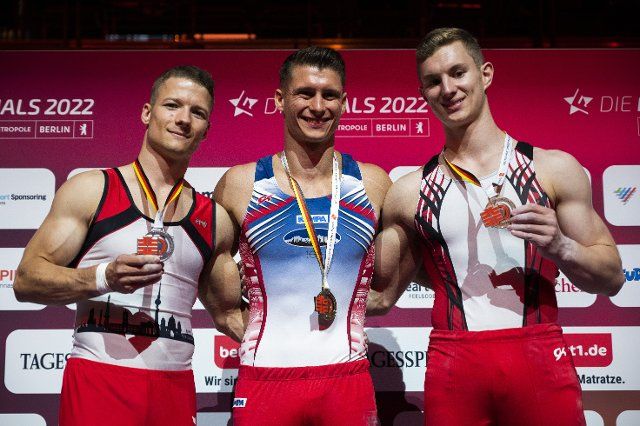 23 June 2022, Berlin: Gymnastics: German championship, decision all-around, men. Lukas Dauser (M), 1st place, Philipp Herder (l), 2nd place and Glenn Trebing, 3rd place stand on the podium after the competition. Photo: Christophe Gateau\/dpa