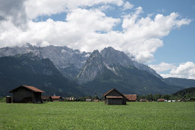 25 June 2022, Bavaria, Garmisch-Patenkirchen: Several barns stand in the meadows in front of the Alpine massif near Garmisch-Patenkirchen. Germany is hosting the G7 summit (June 26-28) of economically strong democracies. Photo: Daniel Vogl\/dpa