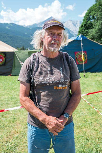 26 June 2022, Bavaria, Garmisch-Partenkirchen: York Runte, organizer of the protest camp "Stop G7 Elmau", stands in front of tents on the campground. The first day of the summit will be about the global economic situation, climate protection and foreign and security policy - especially sanctions against Russia. Photo: Daniel Vogl\/dpa