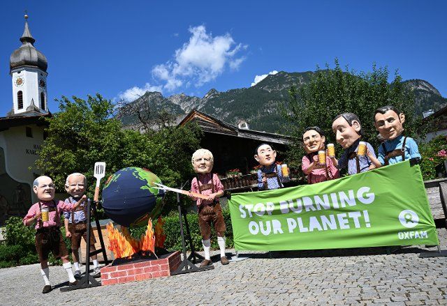 26 June 2022, Bavaria, Garmisch-Partenkirchen: Oxfam demonstrators carry politicians\