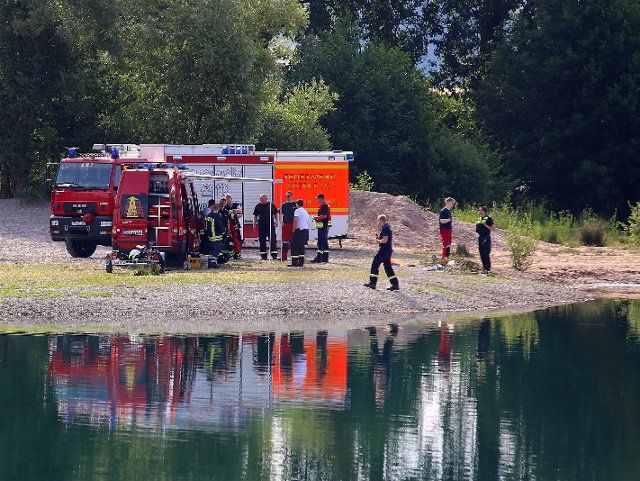 26 June 2022, Lower Saxony, Rosdorf: Vehicles of the fire department stand at a quarry pond. A 25-year-old drowned in a bathing lake in the district of Göttingen. After a large-scale search operation, rescue divers recovered the body from the Rosdorf gravel pond, according to police. Photo: Stefan Rampfel\/DPA\/dpa