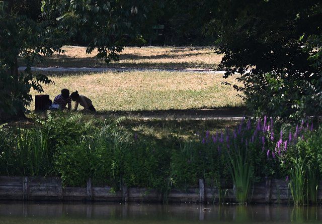 26 June 2022, Berlin: A couple sits on a meadow at the Lietzensee. Photo: Britta Pedersen\/dpa