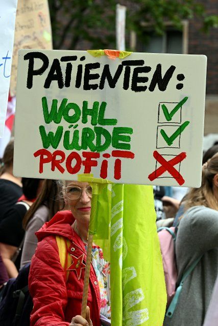 29 June 2022, North Rhine-Westphalia, Duesseldorf: A participant in a protest demonstration by Verdi holds a poster with the inscription "Patients: Welfare - Dignity - Profit". Verdi North Rhine-Westphalia is demonstrating for a "cross-factional effort for hospital staff". Photo: Federico Gambarini\/dpa
