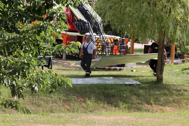 06 July 2022, Thuringia, Bad Sulza: Emergency personnel of the fire department carry a barrier. A sudden sinkhole occurred on the property, killing a man. By means of a camera survey, the authorities want to find out about possible causes for the formation of the sinkhole. Photo: Bodo Schackow\/dpa