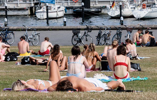 04 August 2022, Schleswig-Holstein, Kiel: In 35 degree heat, people in swimwear and lightly clothed camp on the Reventlou meadow on the fjord. Photo: Markus Scholz\/dpa