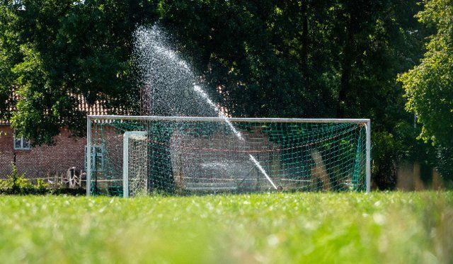 11 August 2022, Lower Saxony, Idensen: The sports field of MTV Idensen is watered with a sprinkler in the midday sun. Photo: Melissa Erichsen\/dpa