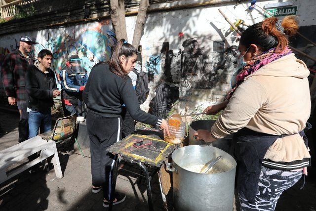 10 August 2022, Argentina, Buenos Aires: A woman pours soup for poor people into a water canister that has been cut to size. In the South American country, the inflation rate has continued to rise. Photo: Claudio Santisteban\/dpa