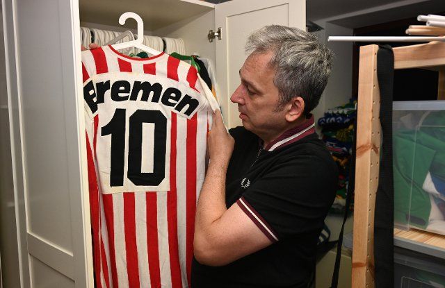 PRODUCTION - 08 August 2022, Bremen: Arnd Zeigler shows a jersey from his collection in his studio . The stadium announcer for Werder Bremen and host of the show "Zeigler\