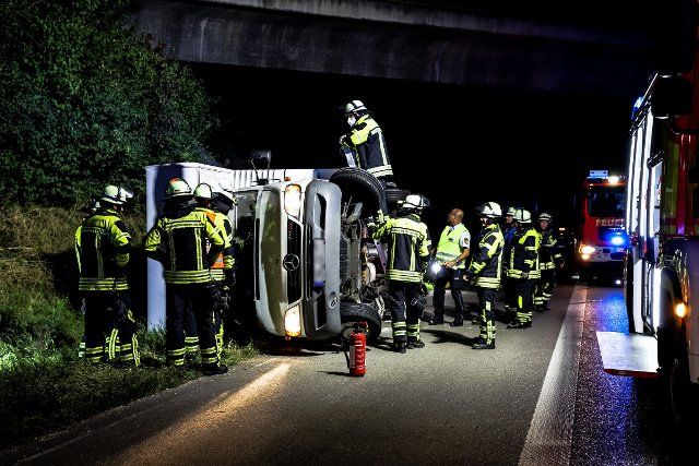 11 August 2022, Baden-Wuerttemberg, Bab8 Kirchheim unter Teck: Firefighters work on a motor home at the scene of an accident on the Autobahn 8 (A8). In an accident caused by a burst tire on a motor home, a woman was seriously injured on the highway 8 near Kirchheim unter Teck (Esslingen district). Due to the broken rear wheel, the motor home skidded on Thursday evening, left the road and tipped onto the right shoulder, police said. The 45-year-old driver and a passenger were uninjured. Another female passenger was taken to hospital with serious injuries. The A8 was closed for a short time in the direction of Munich. Photo: Kaczor\/SDMG\/dpa