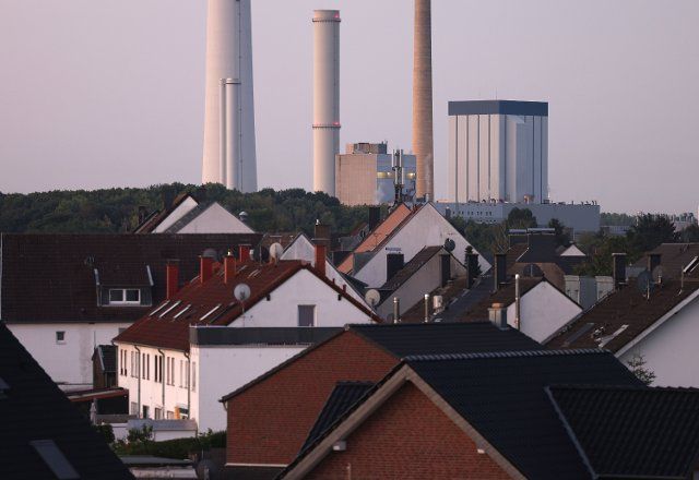 12 August 2022, North Rhine-Westphalia, Cologne: The combined heat and power plant Cologne Merkenich of the energy provider RheinEnergie can be seen behind residential buildings. The power plant generates district heating from lignite and natural gas. Photo: Oliver Berg\/dpa