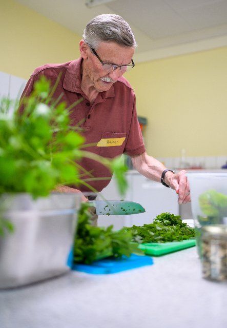 PRODUCTION - 30 June 2022, Lower Saxony, Lüneburg: Participant Rainer prepares salad at the cooking group for grieving widowers. The members of the small group, which meets once a month in Lüneburg to cook, are between 59 and 87 years old. A professional guides the widowers. (to dpa-KORR "Cooking group for grieving widowers - ready meals are taboo") Photo: Philipp Schulze\/dpa