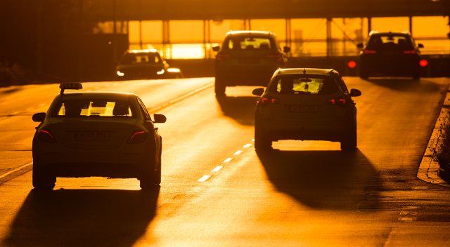 12 August 2022, Lower Saxony, Hanover: Cars drive along a road bathed in warm light from the rising sun. Photo: Julian Stratenschulte\/dpa