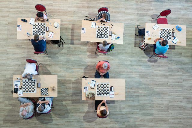 12 August 2022, Saxony, Bautzen: Participants of the international chess tournament "Bautzener Türme Open" sit in front of a chess board in the Stadthalle Krone. The Bautzen Chess Week will take place both as a tournament from 09 to 14 August 2022 and for all interested parties at various locations in downtown Bautzen. Photo: Sebastian Kahnert\/dpa\/ZB
