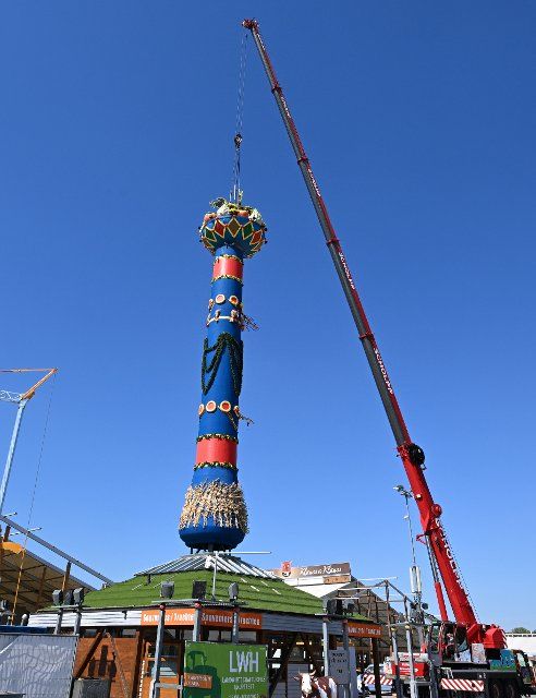 12 August 2022, Baden-Wuerttemberg, Stuttgart: The fruit column, the landmark of the Cannstatter Wasen folk festival, is erected after a two-year break from Corona. The folk festival is considered the second largest festival of its kind in the world after the Munich Wiesn. Photo: Bernd Weißbrod\/dpa