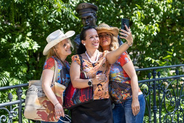 12 August 2022, Hessen, Bad Nauheim: Meike Berger (l), Angela Storm (initiators of the initiative "Elvis in Bronze") (r) and Simone take a selfie with the Elvis stature. The Elvis Festival takes place for the 20th time this year. Elvis Presley was stationed as a soldier in Friedberg from October 1958 to March 1960 and lived in Bad Nauheim. Photo: Hannes P. Albert\/dpa