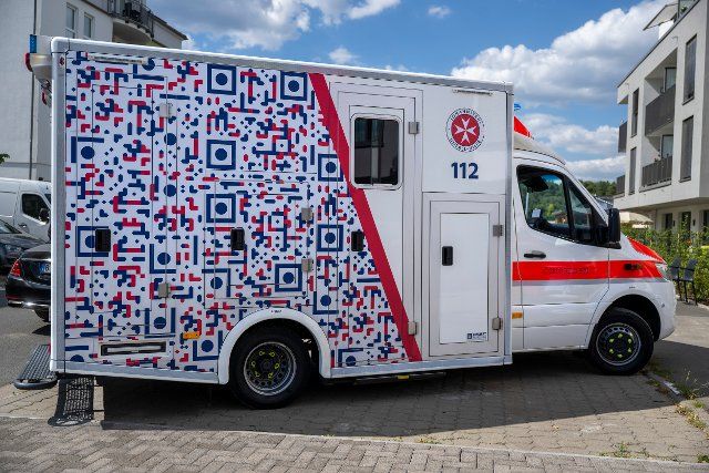 12 August 2022, Brandenburg, Michendorf: An ambulance with an anti-gaffer QR code is parked in front of the entrance to the Johanniter Quarter. When photographing the ambulance covered with large QR codes, a redirection to the page gaffen-toetet.de takes place. Photo: Monika Skolimowska\/dpa