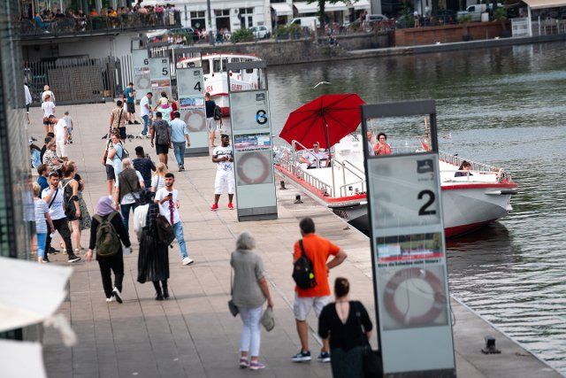 16 August 2022, Hamburg: Numerous people stroll in front of the Alster steamers on the Jungfernstieg at the Binnenalster. Photo: Jonas Walzberg\/dpa