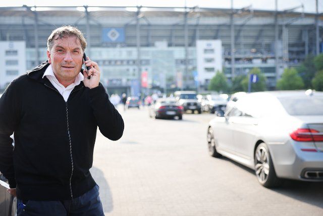 19 August 2022, Hamburg: Soccer: 2nd Bundesliga, Matchday 5, Hamburger SV - Darmstadt 98 at Volksparkstadion. Thomas Wüstefeld, Hamburger SV board member, is on the phone in the parking lot outside the stadium before the game. Photo: Christian Charisius\/dpa - IMPORTANT NOTE: In accordance with the requirements of the DFL Deutsche Fußball Liga and the DFB Deutscher Fußball-Bund, it is prohibited to use or have used photographs taken in the stadium and\/or of the match in the form of sequence pictures and\/or video-like photo series