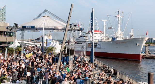 19 August 2022, Hamburg: Visitors stroll to the opening Cruise Days, the Hamburg Cruise Days, on a sunny summer evening at the flood protection site at Baumwall. Until August 21, the shipping companies want to present five large ships. Photo: Markus Scholz\/dpa