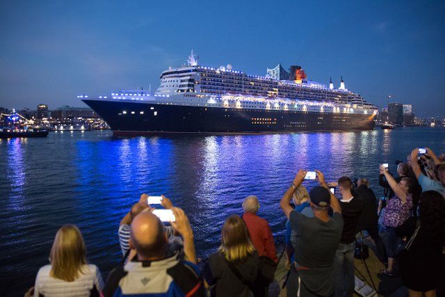 19 August 2022, Hamburg: Numerous visitors watch the Queen Mary 2 cruise ship sail through the Port of Hamburg at the start of Cruise Days. Until Sunday, five ships are expected in the Port of Hamburg for the eighth edition of the cruise festival Hamburg Cruise Days. Photo: Bodo Marks\/dpa
