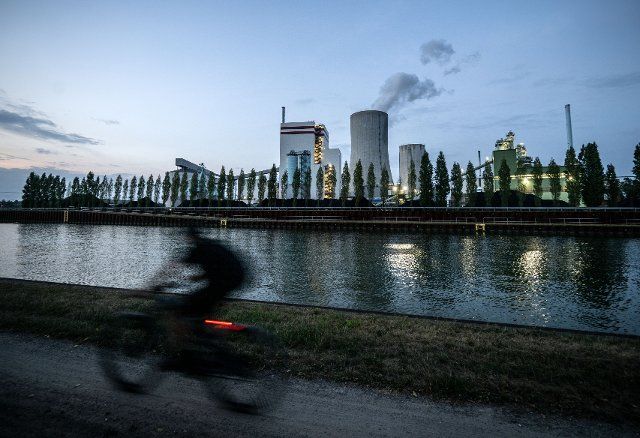 19 August 2022, North Rhine-Westphalia, Lünen: A cyclist rides past the Trianel coal-fired power plant. The 750-megawatt unit has been on the grid since December 1, 2013, and contributes to security of supply. Stadtwerke and regional energy suppliers are the builders and operators of the power plant at Stummhafen in Lünen. Photo: Bernd Thissen\/dpa