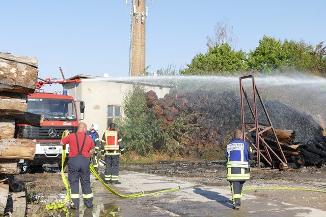 23 August 2022, Thuringia, Niederorsche: Firefighters extinguish a fire in a wood processing company. On the outdoor area of a wood processing company in Niederorschel (district Eichsfeld) has broken out in the night to Tuesday a fire. For as yet unexplained cause, the stored wood went up in flames at about 2:30 a.m., the police reported on Tuesday. Currently, the task forces of the fire department let the fire burn down in a controlled manner. Photo: Gregor Mühlhaus\/dpa-Zentralbild\/dpa