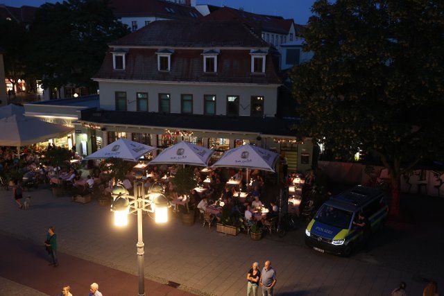 24 August 2022, Thuringia, Weimar: Guests sitting on the terrace of a restaurant at dusk on Theaterplatz. Photo: Bodo Schackow\/dpa