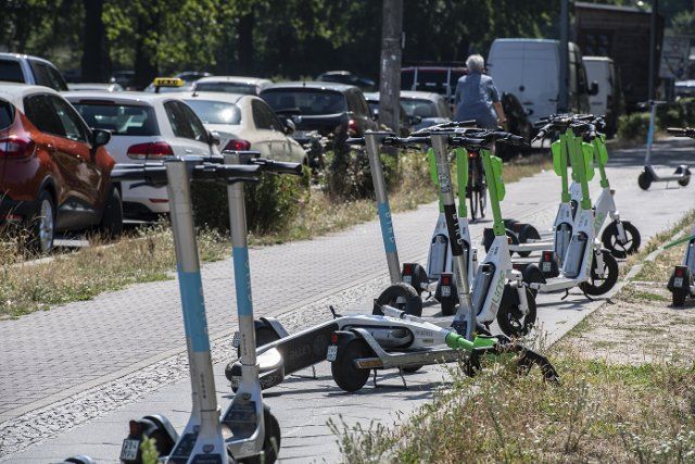 25 July 2022, Berlin: Numerous e-scooters stand on a sidewalk in Treptow. Photo: Paul Zinken\/dpa
