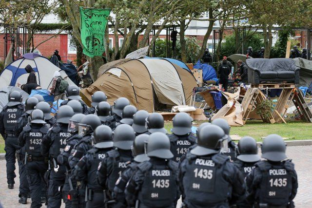 14 September 2022, Hamburg: Helmeted police officers follow the so far voluntary eviction of the punk protest camp in Westerland on Sylt. Previously, the mayor of Sylt had used a megaphone to call on the camp\