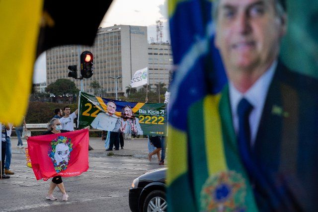 26 September 2022, Brazil, Brasilia: Supporters of current President Bolsonaro and former head of state Lula da Silva promote their candidates with flags and posters in front of motorists at a red light. The presidential elections will take place in the South American country on October 2. Photo: Myke Sena\/dpa