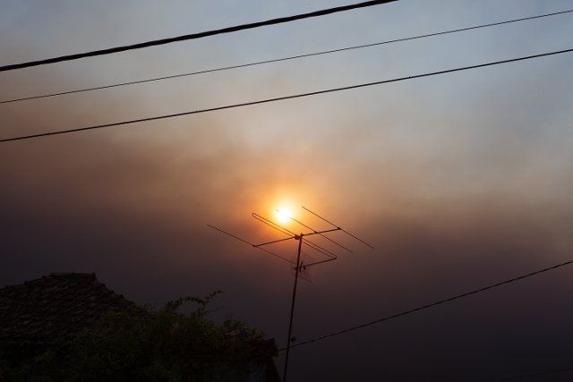 PRODUCTION - 19 August 2022, Portugal, Tomar: The sun shines in the dark sky in a village near Tomar, while the air is filled with smoke and ash from forest fires, brought by hot winds. Photo: Viola Lopes\/dpa