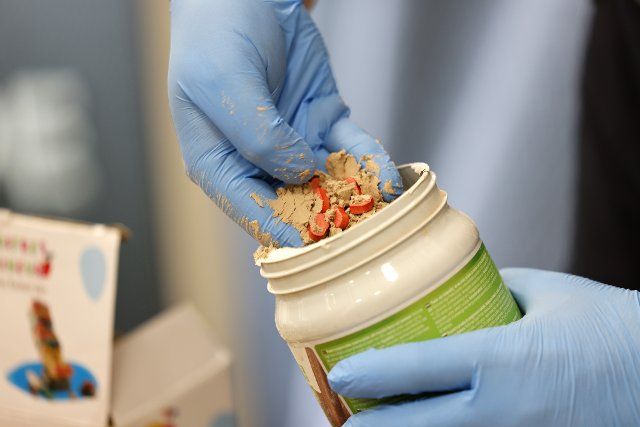 27 September 2022, North Rhine-Westphalia, Cologne: A customs officer shows Ecstasy pills hidden in cans of food supplements. At Cologne Bonn Airport, Cologne Customs found drugs in packages worth around 2.9 million euros. Photo: Thomas Banneyer\/dpa